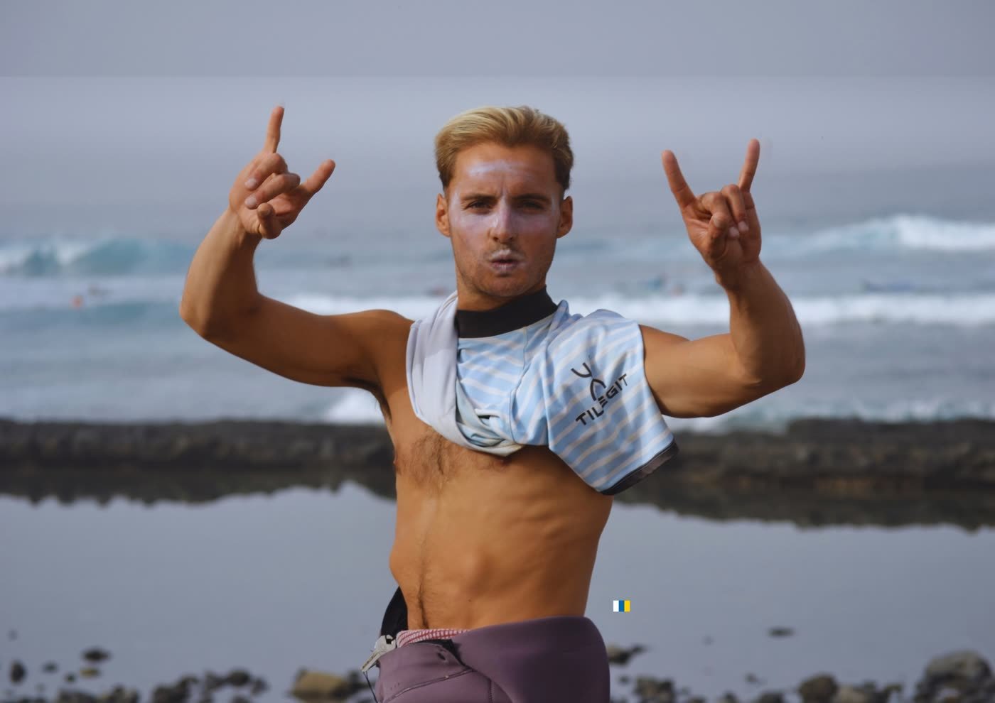 Uno de los hermanos haciendo el saludo surfero en la orilla